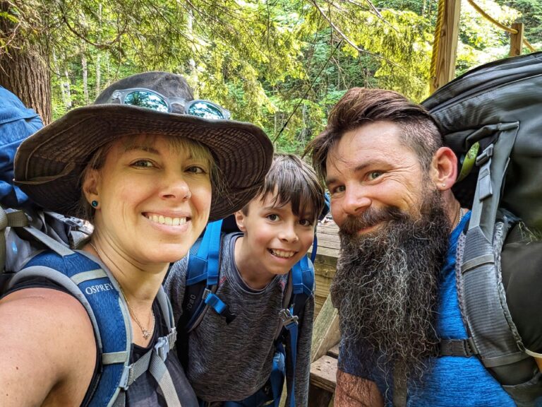 A smiling family with hiking backpacks