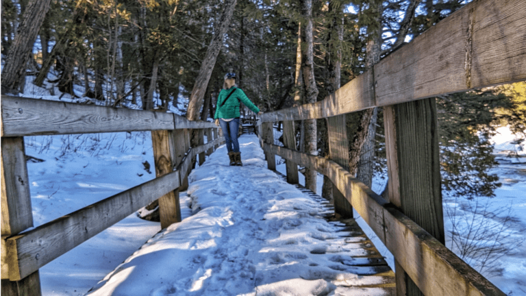 Woman Hiking Across a Snowy Bridge