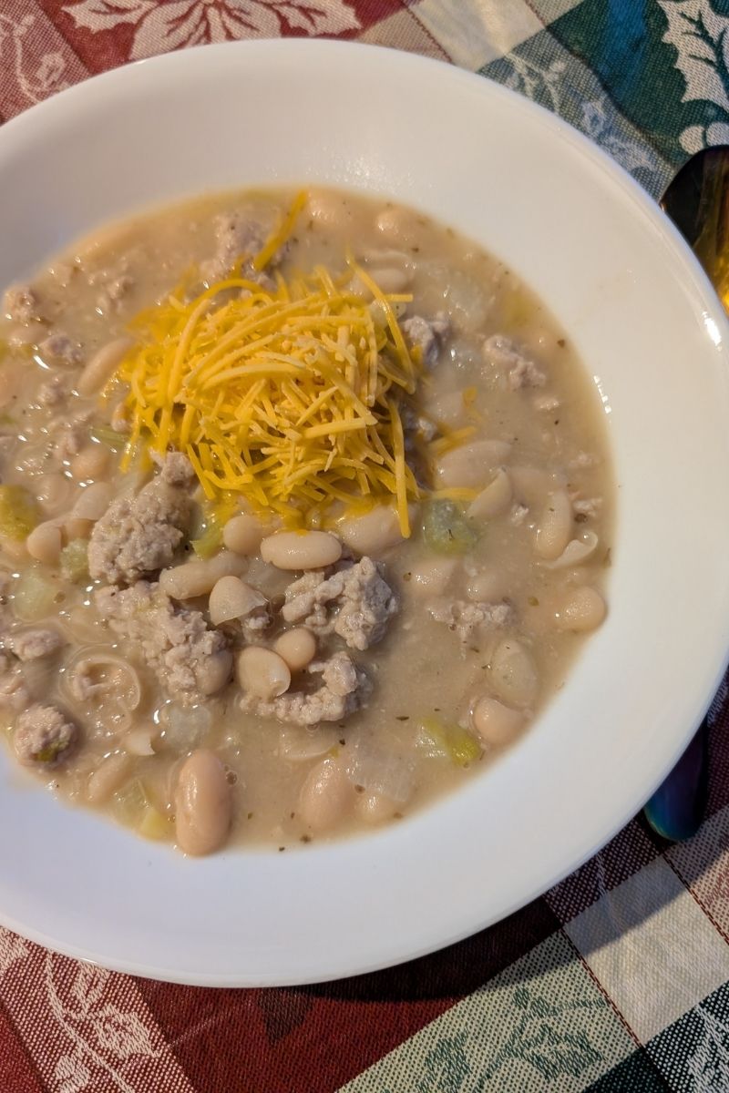 Bowl of Easy White Chicken Chili with Cannellini Beans, topped with shredded cheddar cheese