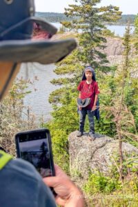 Woman taking picture of boy on rock